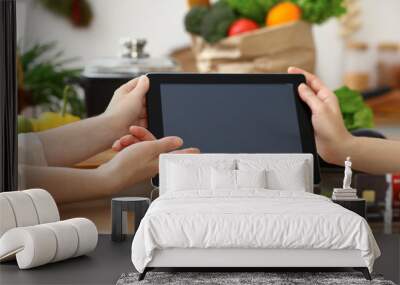 Close-up of human hands using tablet or touch pad. Two women in kitchen. Cooking, friendship or online shopping concepts Wall mural