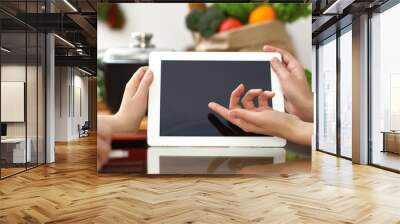 Close-up of human hands using tablet or touch pad. Two women in kitchen. Cooking, friendship or online shopping concepts Wall mural