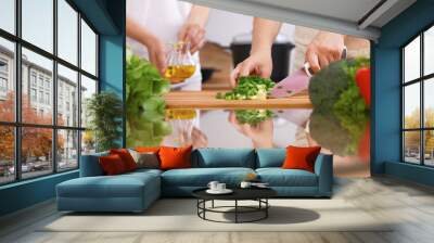 Closeup of human hands cooking in kitchen. Mother and daughter or two female friends cutting vegetables for fresh salad. Healthy meal, vegetarian food and lifestyle concepts Wall mural