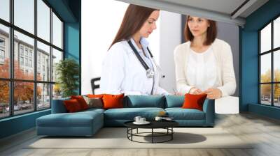 Doctor and  patient  discussing something while standing near reception desk in emergency hospital. Physician at work in clinic. Medicine and health care concept Wall mural