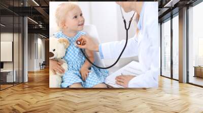 Doctor examining a little blonde girl with stethoscope.Medicine and healthcare concept Wall mural