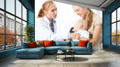 Doctor examining a little boy with stethoscope. Mother holds her son on her lap. Motherless and medicine concept Wall mural