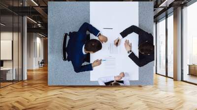 Group of business people and lawyer discussing contract papers sitting at the table, view from above. Businessman is signing document after agreement done Wall mural