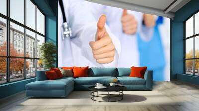 Group of doctors showing OK or approval sign with thumb up. High level and quality medical service, best treatment and patient care concept Wall mural