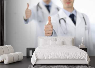 Two male doctors standing as a team and showing thumbs up as a symbol of the best service for patients in the clinic. Medicine and health care Wall mural