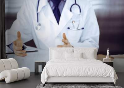 Unknown male doctor and patient woman discussing something while sitting in clinic and using clipboard. Best medical service in hospital, medicine, pandemic stop Wall mural