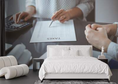 Woman accountant using a calculator and laptop computer while counting taxes for a client. Business audit and finance concepts Wall mural