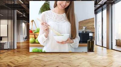 Young happy woman cooking in the kitchen. Healthy meal, lifestyle and culinary concepts. Good morning begins with fresh salad Wall mural