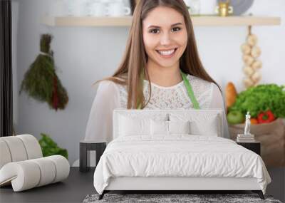 Young happy woman is cooking or eating fresh salad in the kitchen. Food and health concept Wall mural