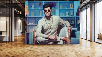 young indian man sitting wearing traditional cloth and jewelry chain bracelet. show peaces in backgr Wall mural