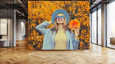 Autumn portrait of beautiful happy smiling woman with yellow maple leaves in hat, coat in the park Wall mural