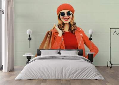 Autumn portrait of beautiful happy smiling young woman with shopping bags wearing red jacket, beret on gray background Wall mural