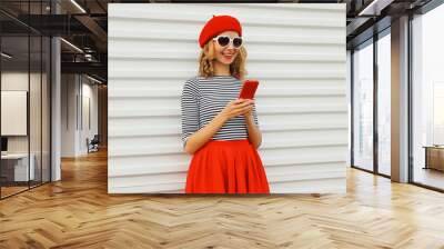 Beautiful happy smiling young woman with smartphone, stylish pretty girl holding phone, red hat Wall mural