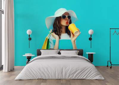 Fashion portrait of beautiful young woman with colorful shopping bags drinking juice in summer hat Wall mural