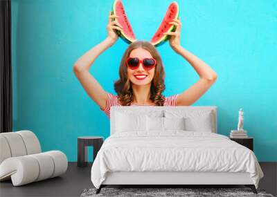 Happy pretty smiling woman is holding slice of watermelon over a colorful blue background Wall mural