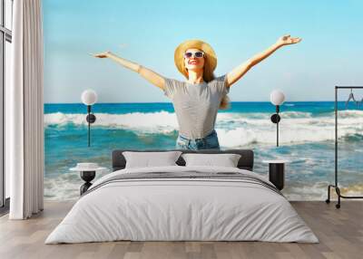 Happy smiling woman enjoys the fresh smell of the sea on a summer day at the beach Wall mural