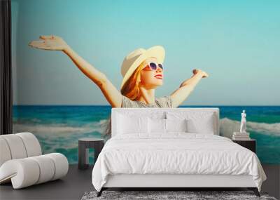 Happy smiling woman raising her hands up on the beach on sea background at summer day Wall mural