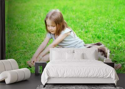 Little girl child sitting on the grass does yoga stretching exer Wall mural