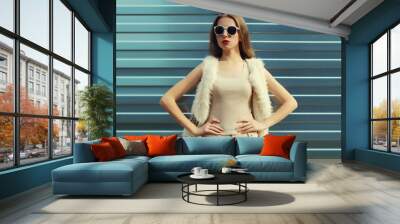 Modern stylish young woman in white fur vest, glasses, fashionable girl posing on gray background Wall mural