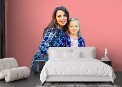 Portrait of stylish smiling mother and child girl on pink background Wall mural