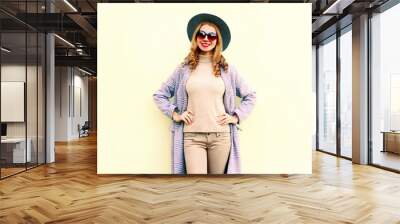 Pretty smiling woman in pink coat, round hat posing on wall background Wall mural