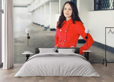 Pretty young woman dressed a red jacket outdoors in the city Wall mural