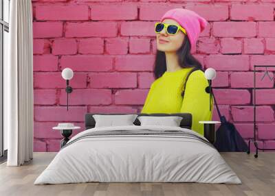 Stylish young teenager girl posing in vivid yellow colorful clothes on pink brick wall background Wall mural