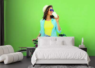 Summer colorful image of happy smiling young woman with bicycle on vivid green background Wall mural