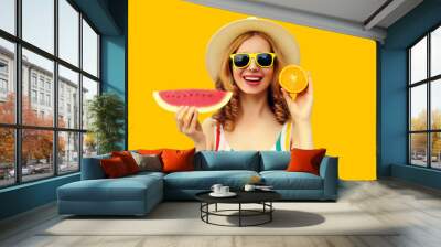 Summer portrait of happy young woman with slice of watermelon and orange fruits on yellow background Wall mural