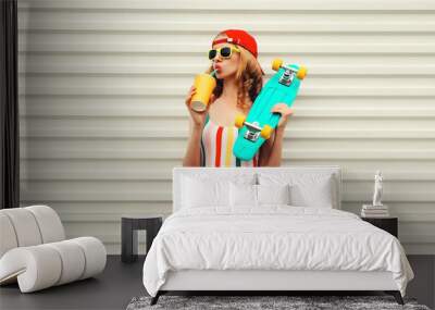 Summer stylish relaxed modern young woman with skateboard drinks fresh juice in colorful clothes Wall mural