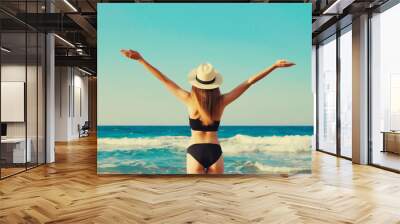 Summer vacation, beautiful happy woman in bikini swimsuit raising her hands up on the beach at sea Wall mural