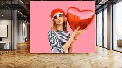 Sweet portrait of beautiful happy woman with red heart shaped balloon blows kiss Wall mural