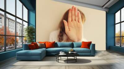 Upset young woman shows stop, no or enough sign with palm of hand, refusal gesture, domestic violence Wall mural