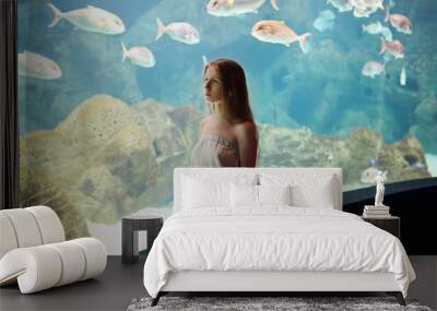 Woman in the aquarium looking on the fishes Wall mural