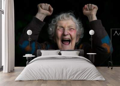 Jubilant elderly woman raises her fists in the air and cheers with excitement, expressing a feeling of triumph Wall mural