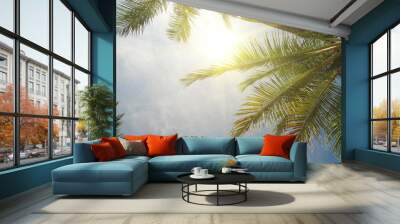 Palm trees and bright sun on blue sky background Wall mural