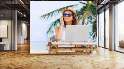 Young woman working in laptop on the beach. Freelance work Wall mural