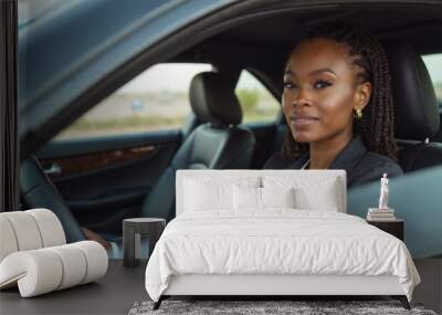 A Black woman dressed in a grey blazer and white shirt, sits in the driver's seat of a car, looking directly at the camera with a confident expression. She is holding the steering wheel with one hand, Wall mural