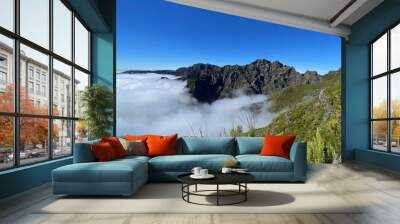 a breathtaking view of madeira’s mountain peaks rising above a blanket of clouds, with vibrant green Wall mural