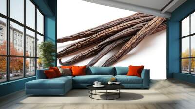 A group of organic vanilla beans lies on a clean, white surface, displaying their dark, wrinkled texture, perfect for flavoring desserts and beverages Wall mural