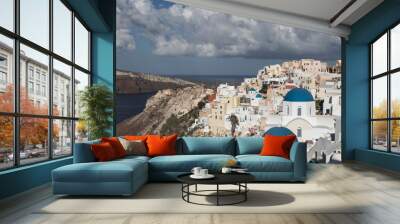 Oia town on Santorini island in Greece. The background is a blue sky with dark clouds. View of white houses Wall mural