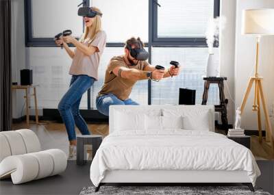 caucasian couple playing video games in virtual reality glasses. Joyous Man and woman wearing virtual reality goggles for mazing experience in abstract vr world, at home in living room. copy space Wall mural