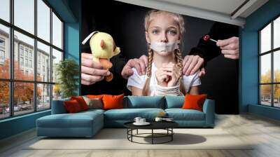 Child abuse. Abduction of children. Slavery and the sale of people. Psychological violence.Scared caucasian little girl is afraid of man in black, kidnapping her. Isolated on black studio background Wall mural