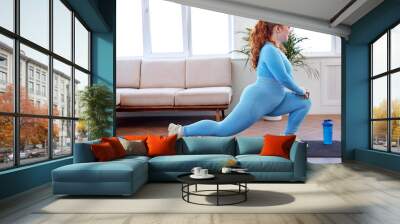 Chubby Redhead Woman Doing Lunges On Mat, Engaged in Fitness, At Home, Wearing Blue Sportive Outfit, Stretching Body, Warming Up Muscles, Lead Healthy Lifestyle. Oversize Plus Size Model Workout Wall mural