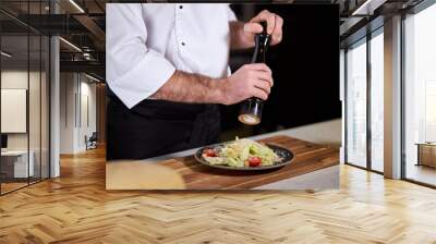 cropped chef adding spices to salad, finishing meal, wearing white apron uniform, at work in kitchen. delicious, tasty, yummy food concept Wall mural