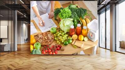 Dietologist writing healthy diet plan for patient with healthy food on table, Right nutrition concept Wall mural