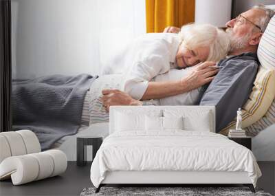 elderly woman hugging sick husband lying on bed Wall mural