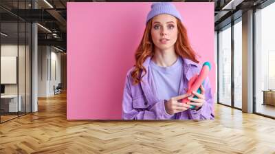 female enjoy clitoral vaginal vibrator to satisfy herself posing at camera with it, isolated on pink background Wall mural