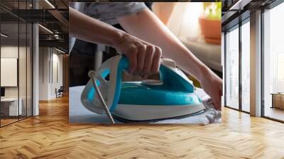 Female hands ironing white shirt on ironing board. Wall mural