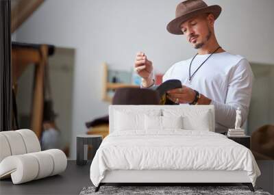 male hats maker standing at his atelier workshop, holding perfectly made hat for customers. successful adult business man employed at his own business Wall mural